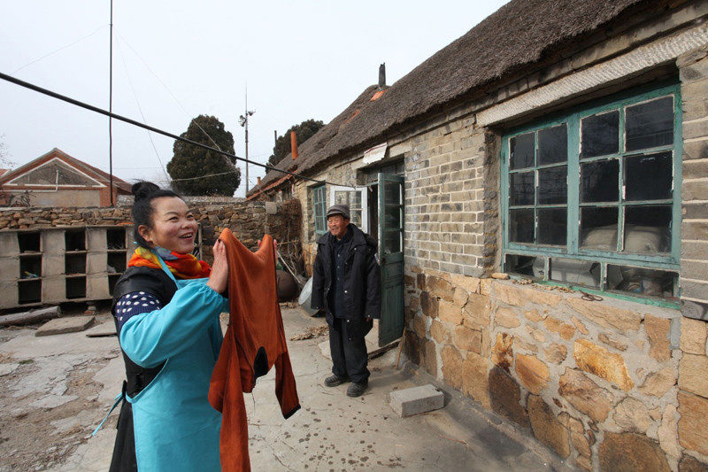 图为：12月14日，在山东省威海市文登区侯家镇崔家村，养老服务中心的服务员李清华（左）来到崔同春老人家，帮助老人清洗晾晒衣物。